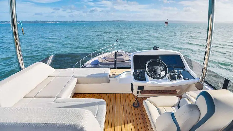 Luxury boat interior featuring a stylish helm, plush seating, and panoramic views of calm waters under a blue sky.